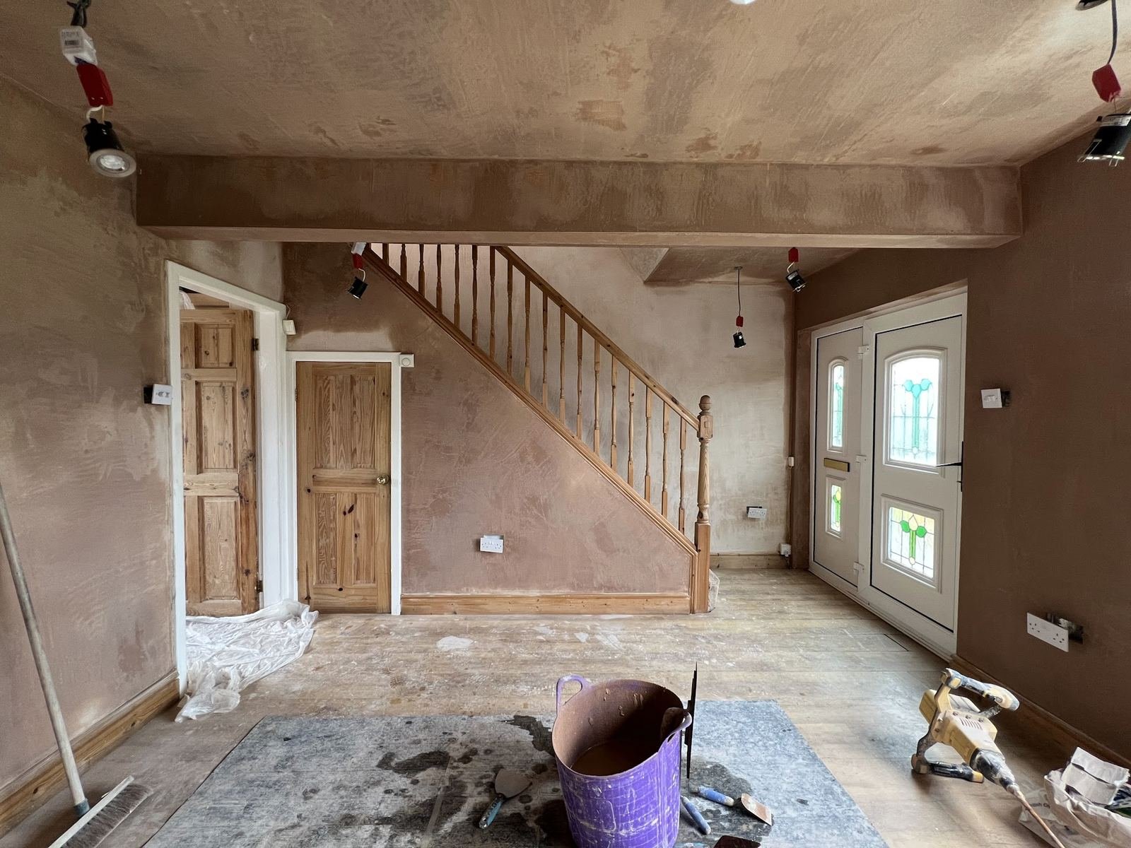 Hallway and staircase freshly plastered, the pink skim still drying